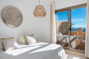 A bedroom with a bed, a hanging light fixture, and a view of the outside. - Premium Penthouse with Unmatched Views (Benahavís)