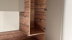 Ein Holzkabinent mit heller Innenseite, teilweise geöffnet, zeigt eine Holzvertäfelung mit strukturierter Oberfläche.