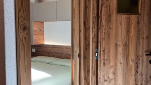 Eine Holztür, die in ein Schlafzimmer mit einem Bett und einem Kopfteil an der Wand führt.