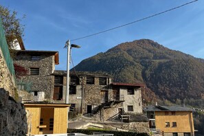 Un pueblo montañoso rústico con edificios de piedra y una imponente montaña al fondo.