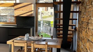 Un comedor con una mesa y sillas de madera, vista al exterior y una escalera.