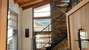 Una escalera con pared de piedra, vigas de madera y barandilla de metal.
