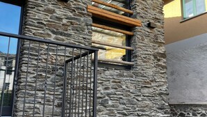 Un edificio de piedra con una verja de metal, vigas de madera y una ventana.