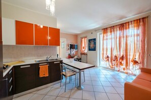 A modern kitchen with dark cabinets, a white countertop, and a dining area with a table and chairs. - Sisy by the Lake—with Wi-Fi, a pool, and a garage (Sirmione)