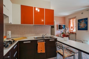 A modern kitchen with dark cabinets, a white countertop, and a large island with an orange towel. - Sisy by the Lake—with Wi-Fi, a pool, and a garage (Sirmione)