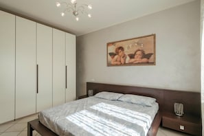 A bedroom with a large bed, a wardrobe, and a painting on the wall. - Sisy by the Lake—with Wi-Fi, a pool, and a garage (Sirmione)