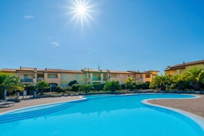 A swimming pool with a curved edge, surrounded by buildings with a Mediterranean architectural style, featuring terracotta roofs and stucco walls. - Sisy by the Lake—with Wi-Fi, a pool, and a garage (Sirmione)