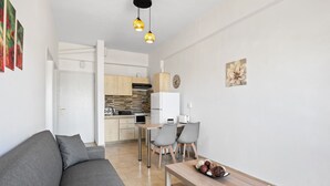 A modern living room with a gray sofa, a wooden coffee table, and a dining area with chairs and a table. - Sun Beach Apartment in Chania 3 (Chania)