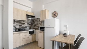 A modern kitchen with wooden cabinets, a microwave, a toaster, and a refrigerator. - Sun Beach Apartment in Chania 3 (Chania)