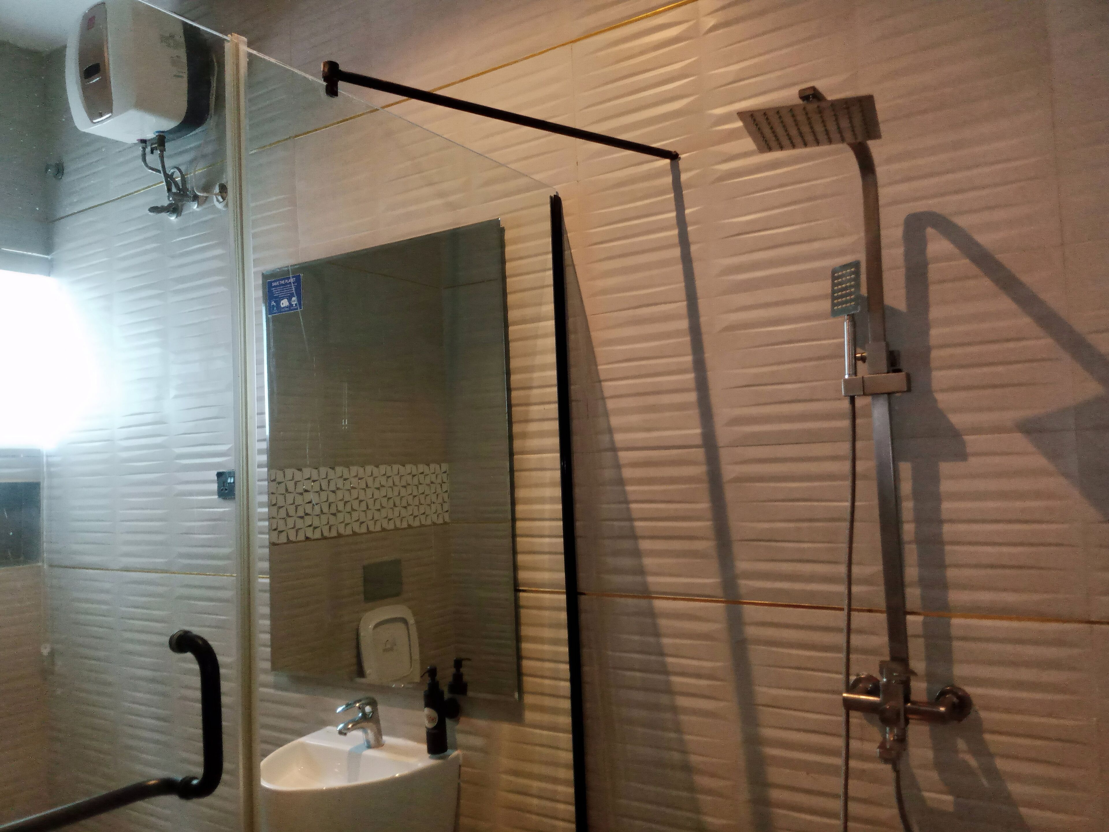 A bathroom with a glass-enclosed shower, a sink, and a mirror.