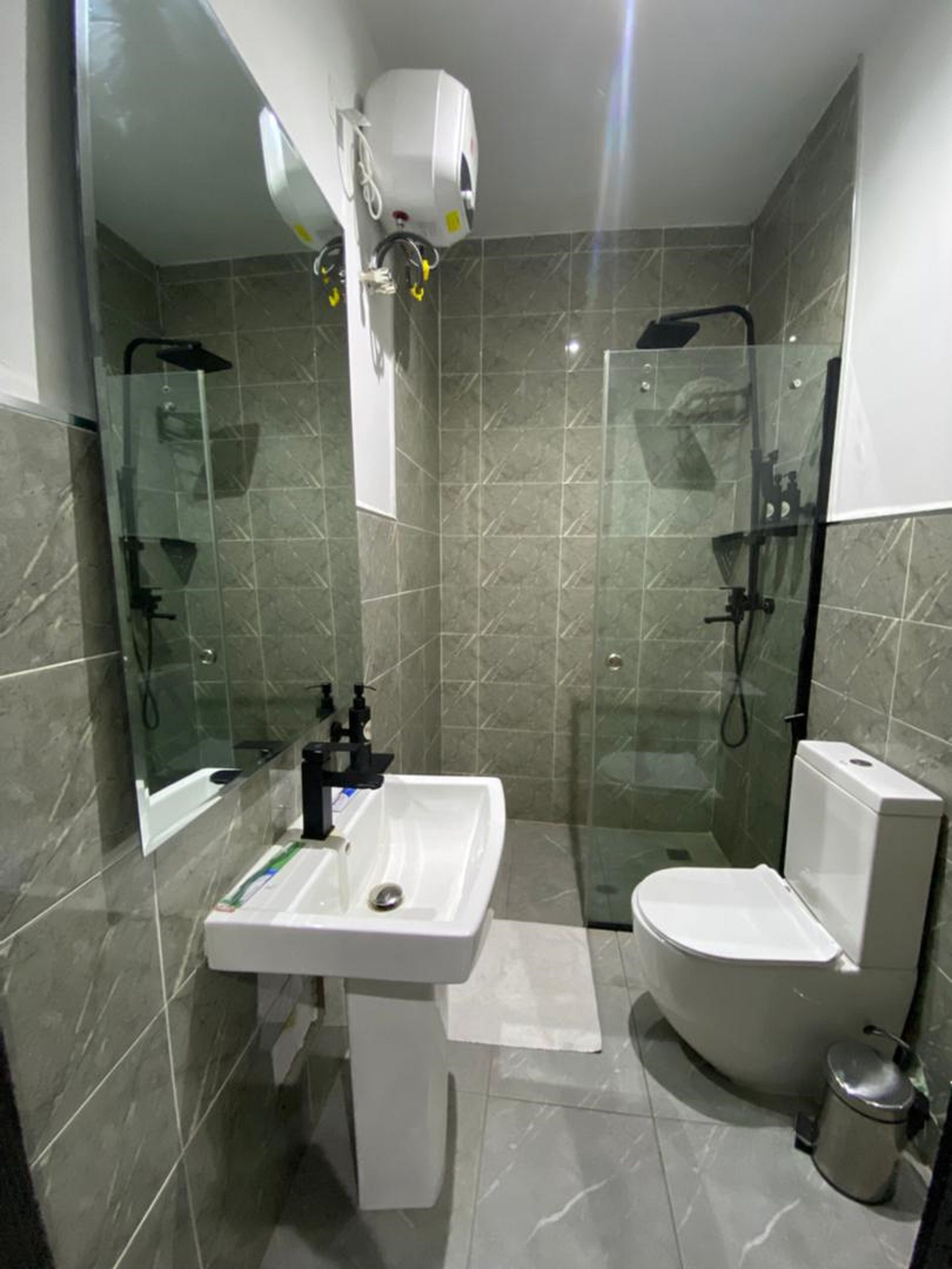 A modern bathroom with a glass-enclosed shower, a white sink, and a toilet.