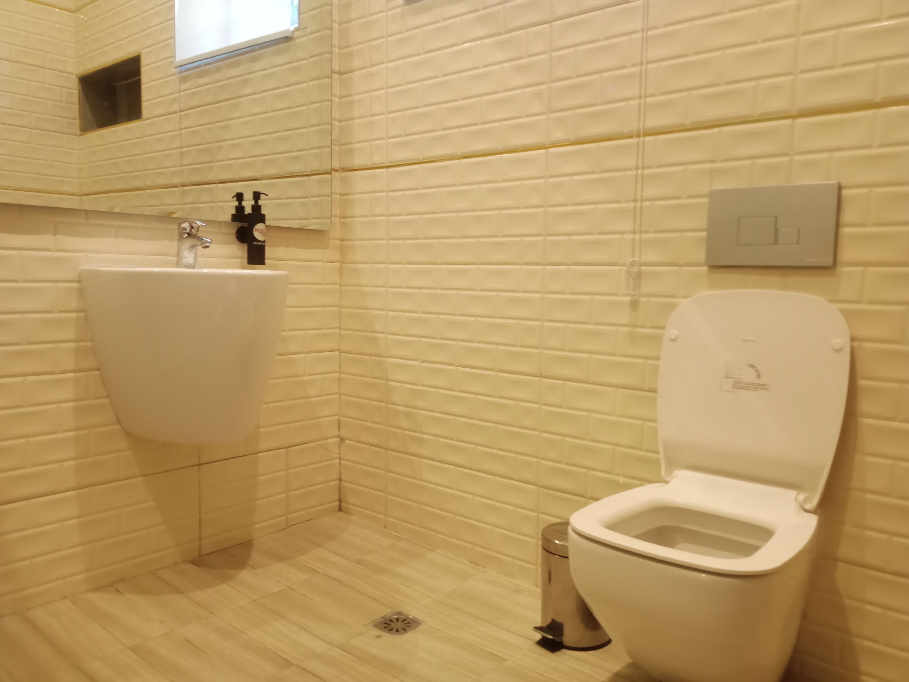 Une salle de bain avec un lavabo blanc, des toilettes et une poubelle.