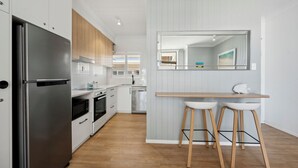 Una cocina moderna con electrodomésticos de acero inoxidable, armarios de madera y una barra con taburetes.