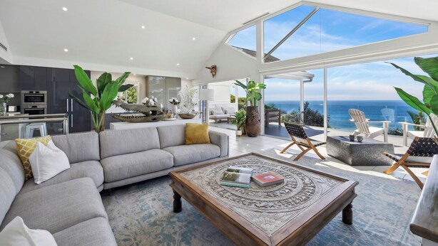 A spacious living area with a large gray sofa, a wooden coffee table, and a view of the ocean through large windows. - Epicview - Incredible views, Pets stay free (SAPPHIRE BEACH)
