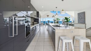 A modern kitchen with a large island, stainless steel appliances, and a view of the ocean. - Epicview - Incredible views, Pets stay free (SAPPHIRE BEACH)