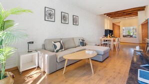 En moderne stue med sofa, sofabord og spiseområde med stole og bord.