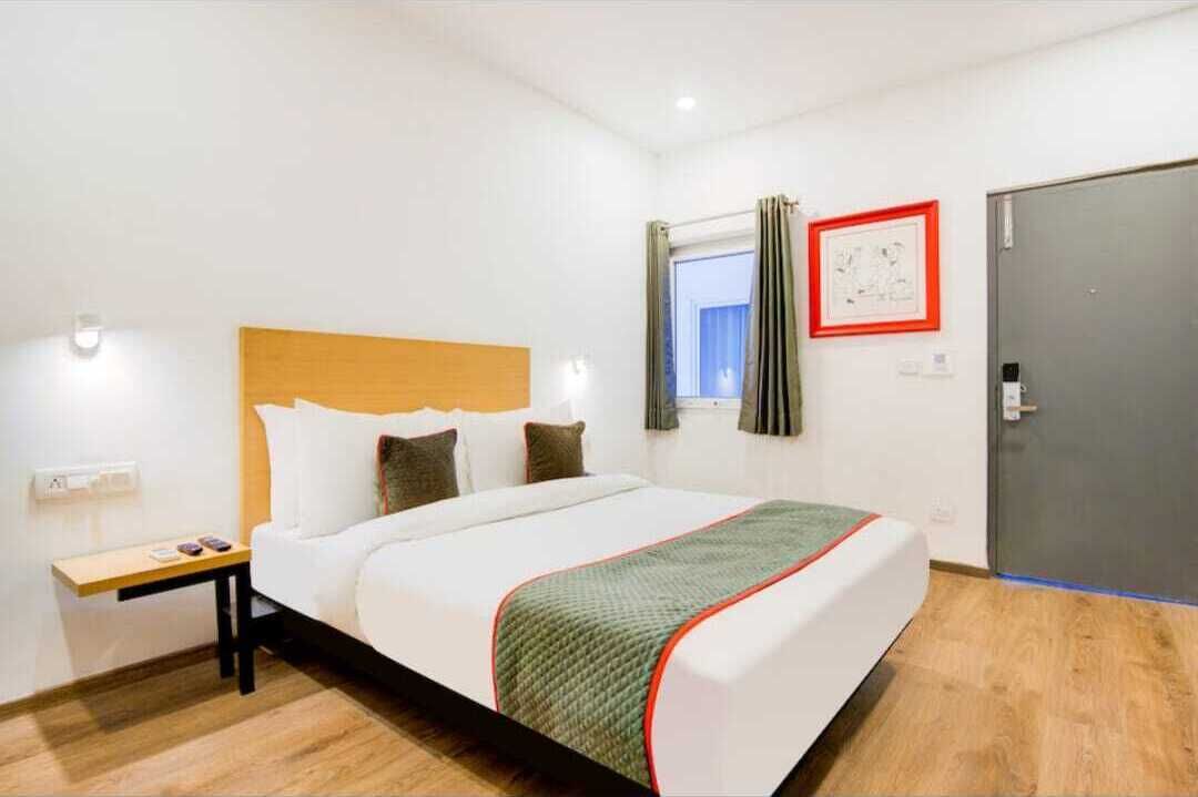 Ein Hotelzimmer mit Bett, Nachttisch und einem Fenster mit Vorhängen.