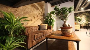 A cozy living room with a leather sofa, a wooden coffee table, and various potted plants. - VTZ The Botanic Hostel (Zaragoza)