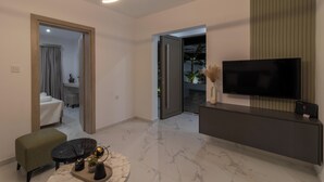 A modern living room with a flat-screen TV, a marble floor, a sofa, and a coffee table. - Melia Villa in Kolympia (Kolympia)