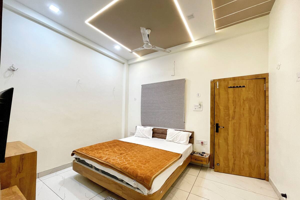 Ein modernes Schlafzimmer mit einem Bett, einer Holztür, einem Deckenventilator und einer gestreiften Wanddekoration.