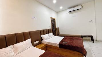 A hotel room with two beds, a wooden headboard, a small bench, an air conditioning unit, and a decorative wall panel.
