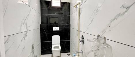 A bathroom with a toilet, a shower, and a sink.