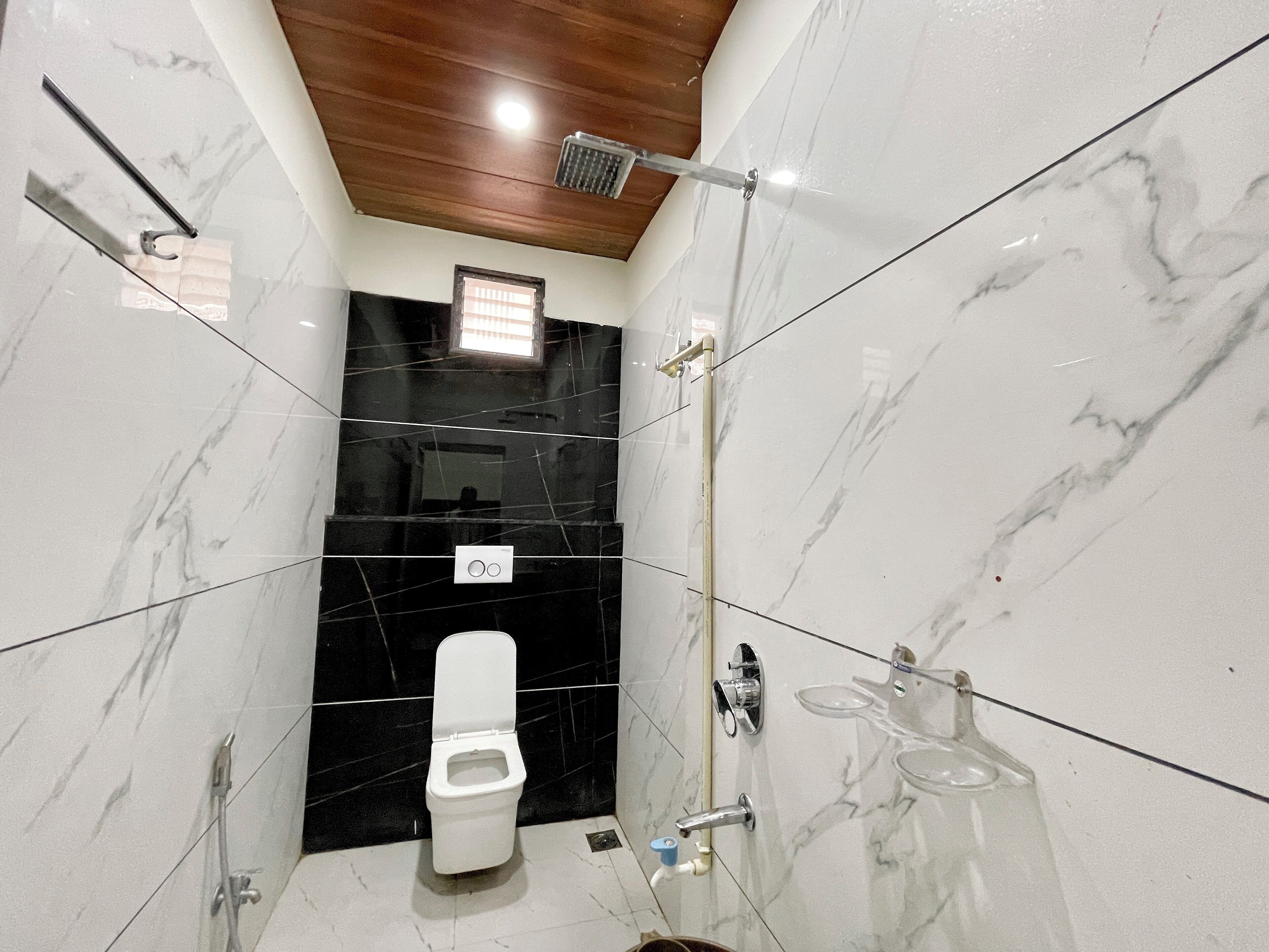 A modern bathroom with a toilet, shower, and hand dryer.