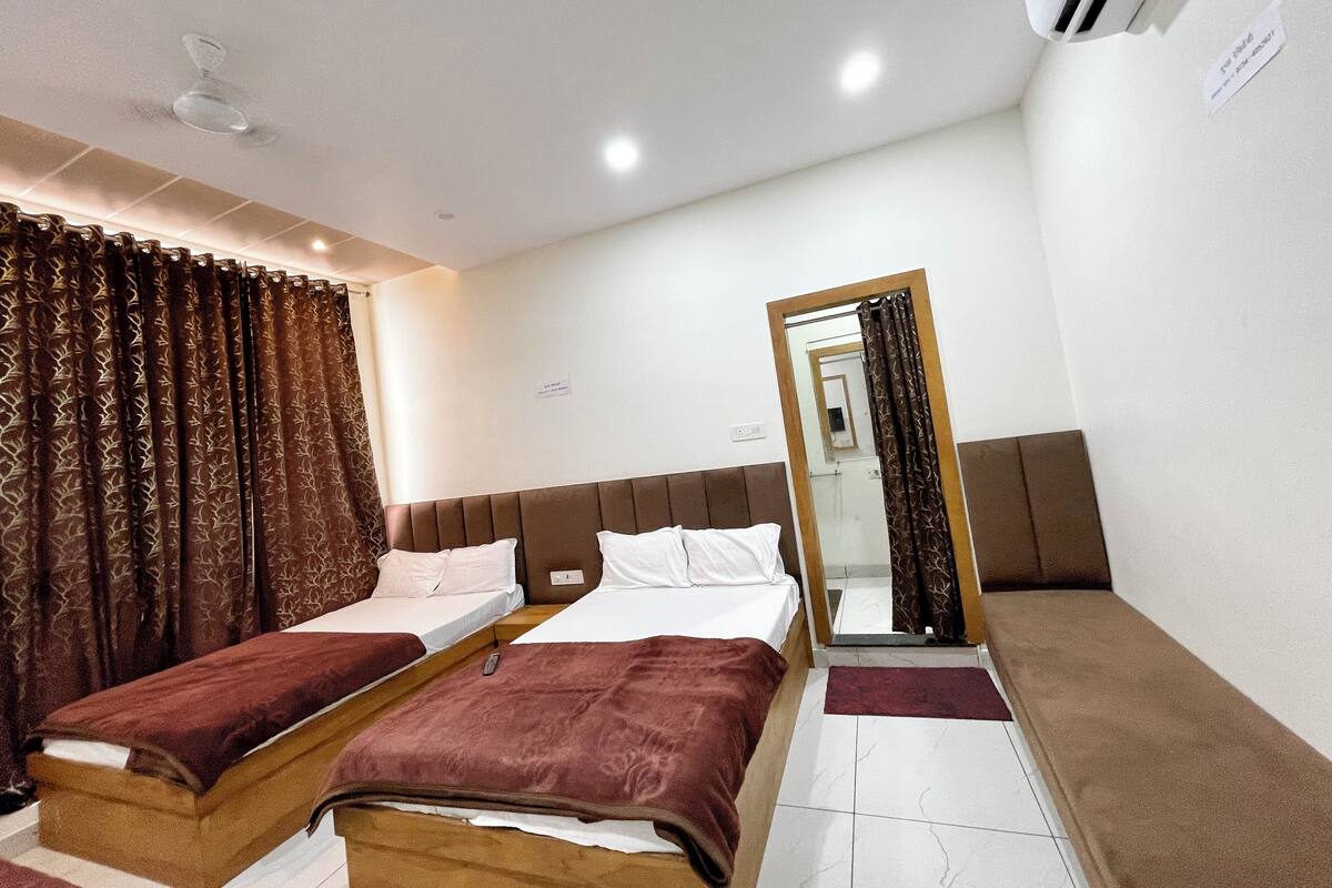 Ein Hotelzimmer mit zwei Betten, einem Spiegel, einem Deckenventilator und einer Wandklimaanlage.