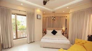 A bedroom with a large bed, a yellow armchair, and a balcony with curtains. - Hotel Dream Heights Hotel and Apartment (Rawalpindi)