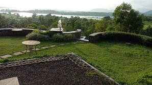 Un jardín con una fuente de piedra, una mesa pequeña y vistas a un lago y montañas.