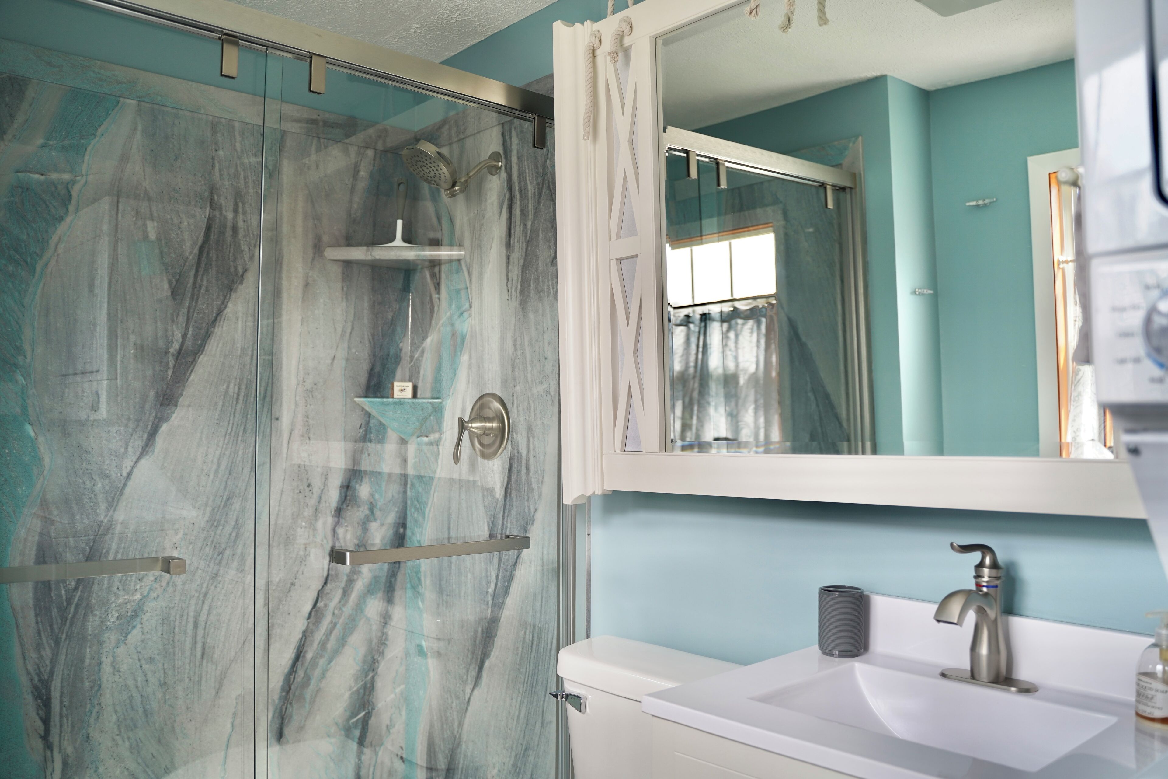 A bathroom with a glass shower enclosure, a white sink, and a large mirror.
