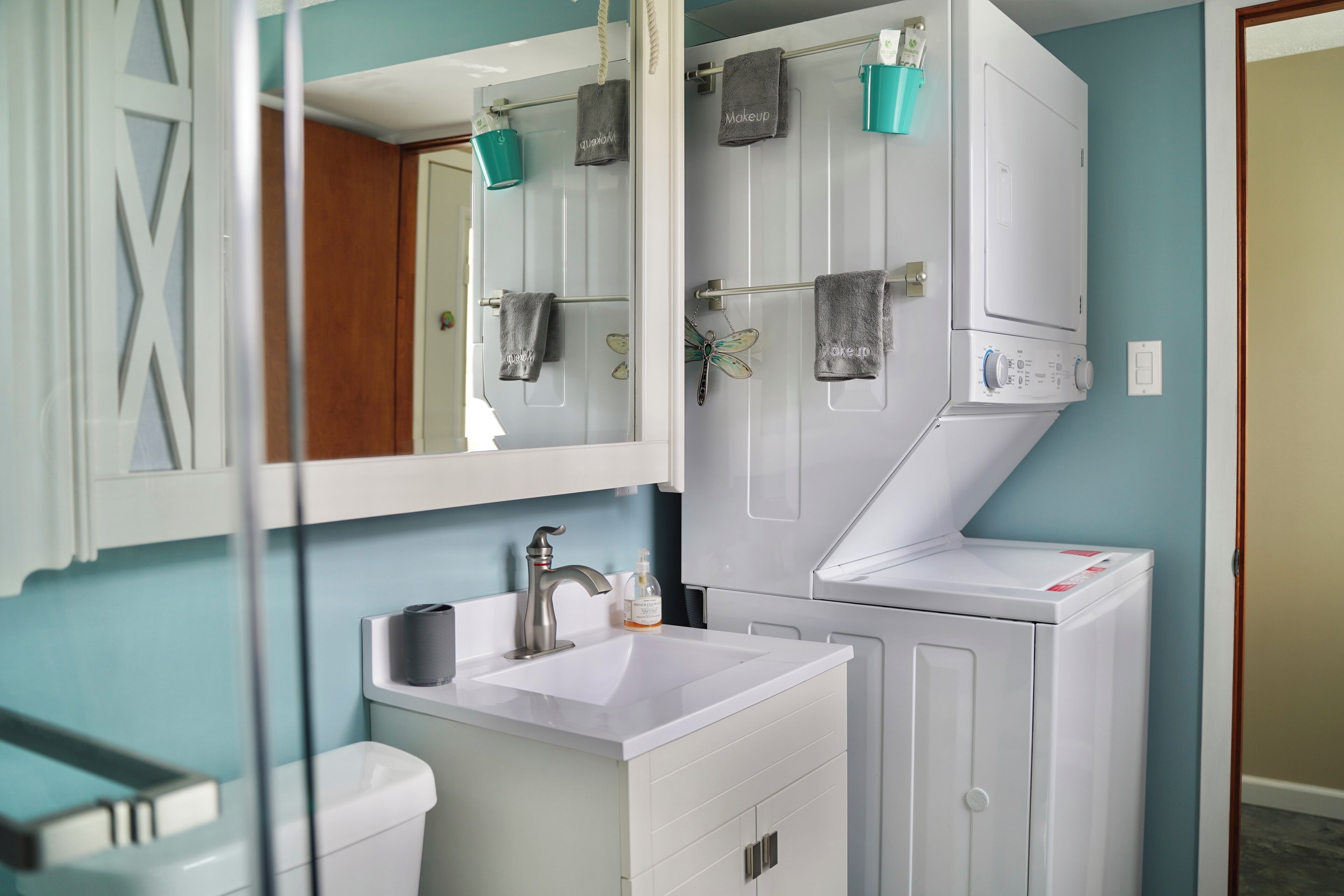 Un baño con lavamanos, espejo, toallero y un inodoro blanco.