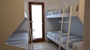 A dormitory room with bunk beds, a door, and a window. - Luisa Apartment In Budoni Shared Pool (Budoni)