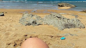 A beach with clear skies, rocky formations, and calm water. - POSADA LA VICTORIA (Miengo)