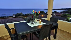Un balcon avec une table dressée pour deux personnes, offrant une vue sur la côte.