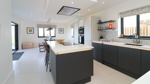 Une cuisine moderne dotée d’un îlot central, d’appareils électroménagers intégrés et d’une grande fenêtre qui laisse entrer la lumière naturelle.