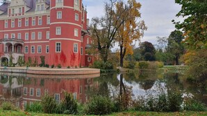 Un edificio grande de color rojo con varias ventanas y un reflejo en el agua.