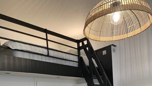 Ein Stockbett mit schwarzer Metallleiter, einer wei ßen Tür und einem Tisch mit Stühlen.