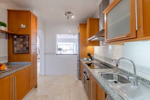 A kitchen with wooden cabinets, granite countertops, a stainless steel sink, and a window providing natural light. - Infinity Haven by Fidalsa (Villamartín)