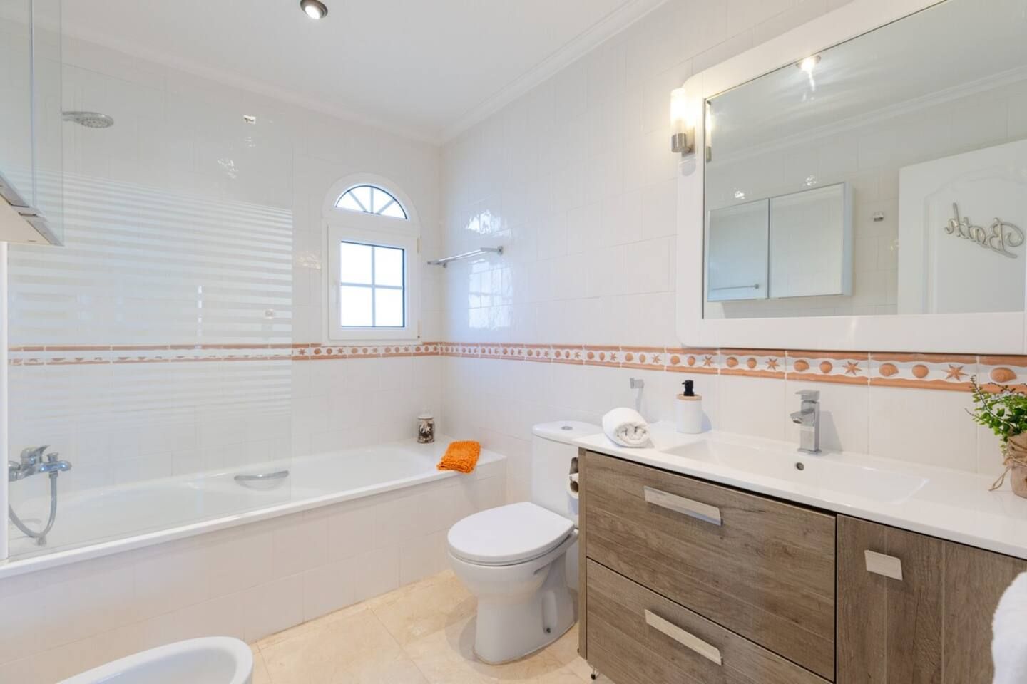 A modern bathroom with a bathtub, toilet, and vanity.