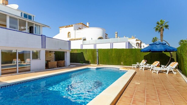 A swimming pool with lounge chairs, a modern house, and a clear sky. - Infinity Haven by Fidalsa (Villamartín)