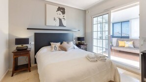 A bedroom with a bed, bedside tables, a lamp, a painting, and a view of a balcony. - Infinity Haven by Fidalsa (Villamartín)