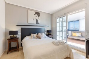 A bedroom with a bed, bedside tables, a lamp, a painting, and a view of a balcony. - Infinity Haven by Fidalsa (Villamartín)