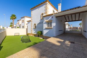 A residential property with a paved driveway, a small lawn with a soccer goal, and a white building with a tiled roof. - Infinity Haven by Fidalsa (Villamartín)
