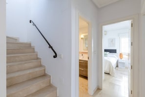 A staircase with a handrail leading to a bedroom with a bed, a nightstand, and a window. - Infinity Haven by Fidalsa (Villamartín)