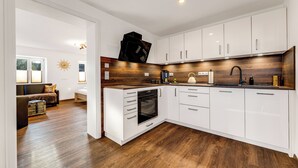 Una cocina moderna con armarios blancos, encimera de madera y horno empotrado.