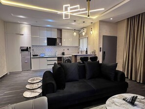 A modern living room with a black sofa, a coffee table, and a dining area with a small table and chairs.