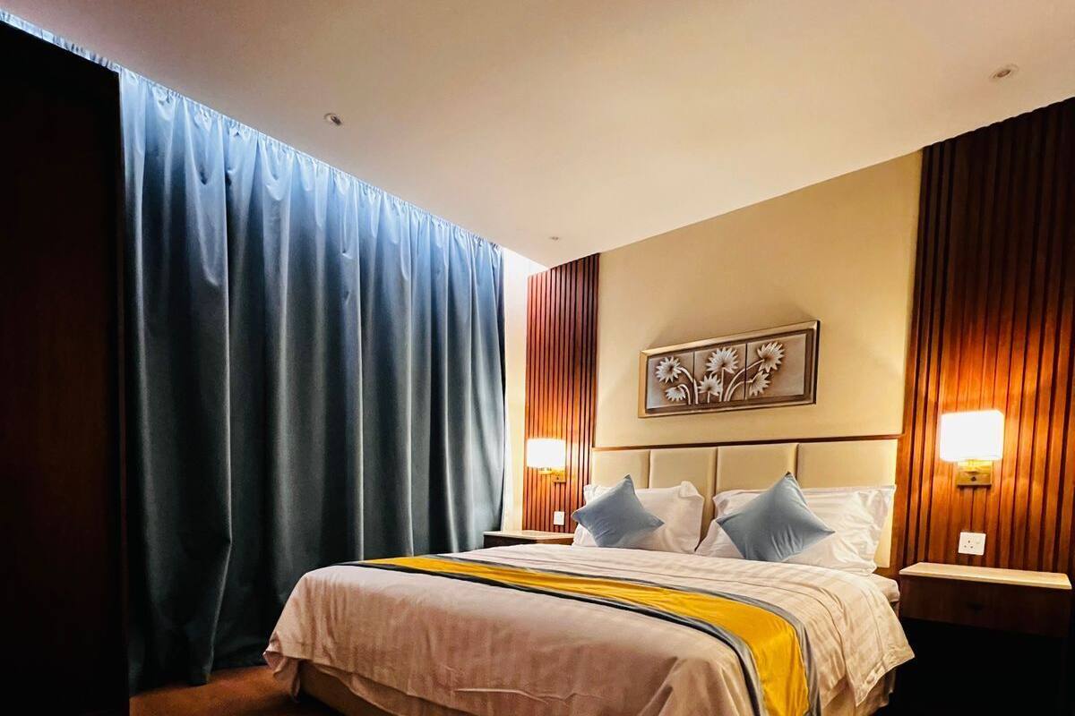 Un hotel moderno con una cama grande, suelo de madera y vistas a la ciudad.