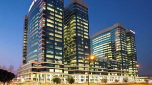 A modern high-rise building with multiple floors, large windows, and a prominent sign at the top. - Pestana Apartment 4 (Riyadh)