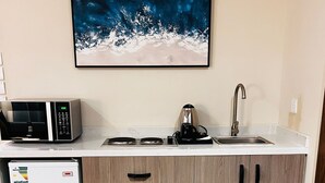 A compact kitchen with a microwave, kettle, and sink. - Pestana Apartment 4 (Riyadh)